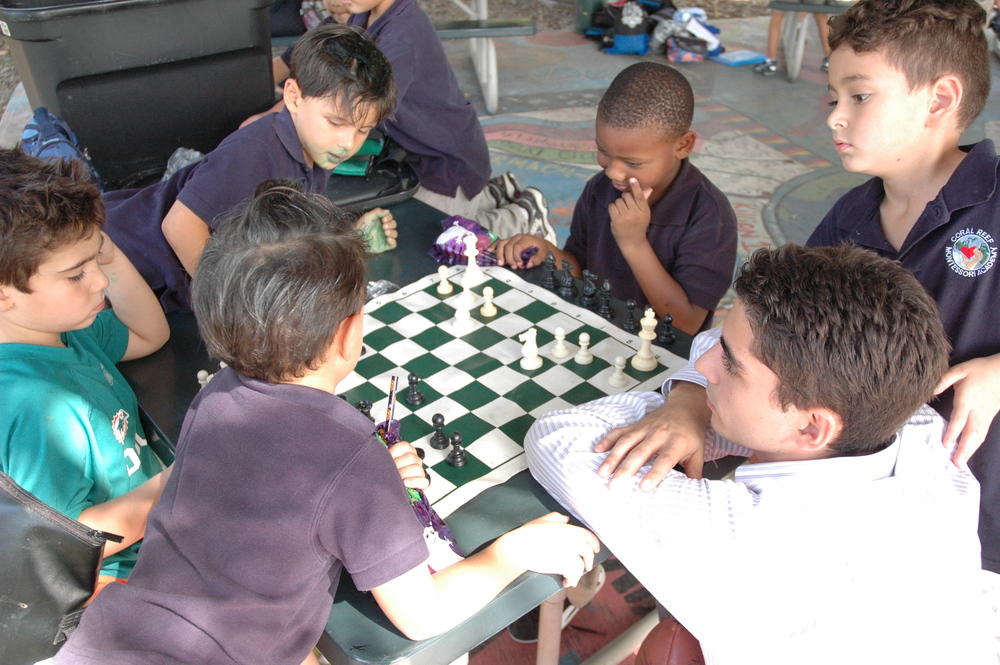 Students gathered around a chessboard during a lesson